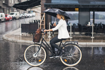 Man riding bicycle on wet street during rainy season