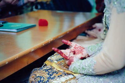 Midsection of bride sitting by table