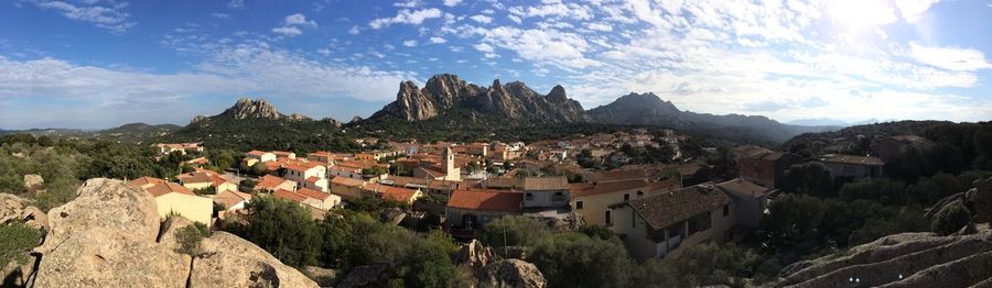 Panoramic shot of town and rocky mountains against sky