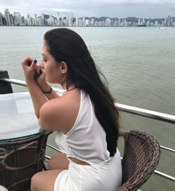 Young woman using mobile phone at sea