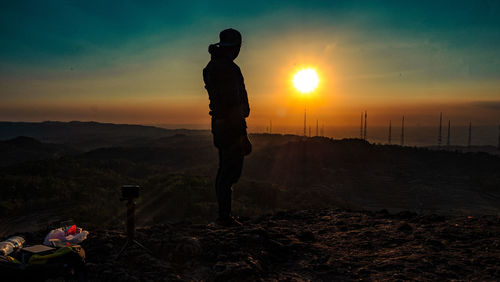 Silhouette man standing on mountain against sky during sunset