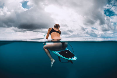 Low angle view of woman sitting on sea against sky