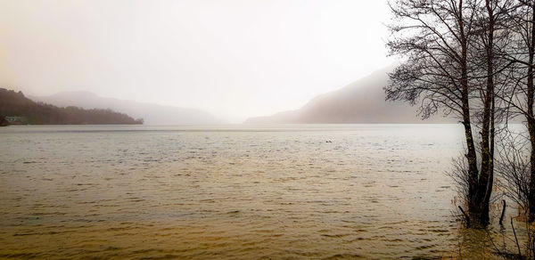 Scenic view of lake against sky during foggy weather