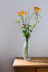 Close-up of flower vase on table against wall