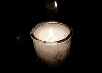 Close-up of lit tea light candle in darkroom