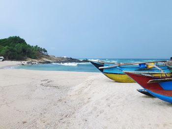 Boat moored on beach against clear sky