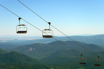 Overhead cable cars over mountains against sky