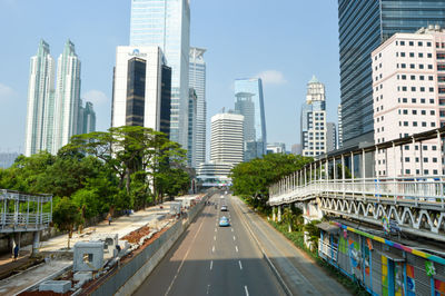 Road amidst buildings in city against sky