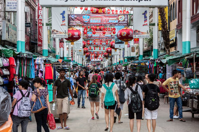 People walking amidst stalls in decorated market