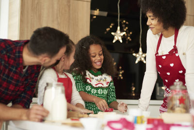 Girl with parents and sister preparing food during christmas in kitchen at home