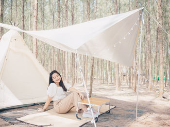 Woman sitting on chair against trees