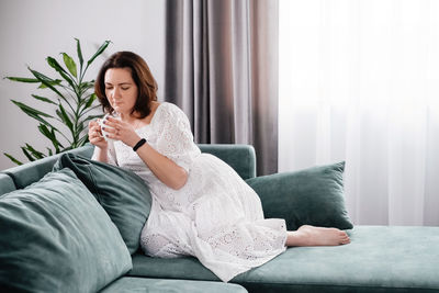 Woman drinking mug of coffee in cozy home atmosphere in the morning. real middle age plus size