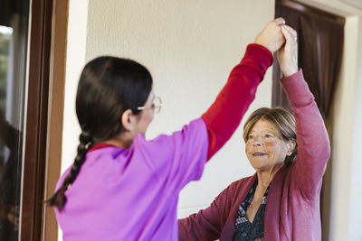 Young caregiver helping senior woman to exercise at home