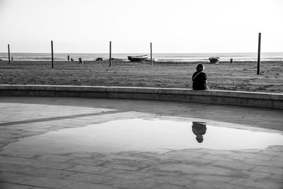 Man fishing on beach against clear sky