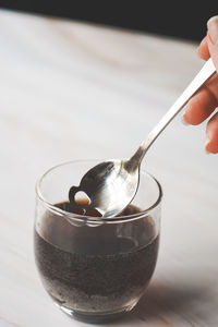 Cropped hand of person pouring into glass on table