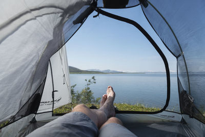 Legs of male backpacker in tent with view over lake virihaure from staloluokta, padjelantaleden trail, padjelanta national park, sweden