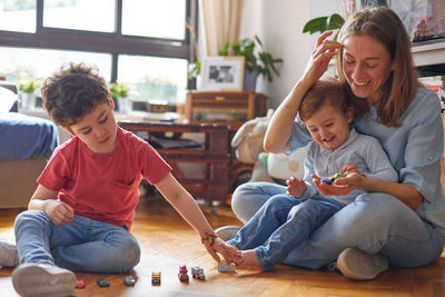 Happy friends playing with baby sitting on floor