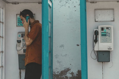 Side view of man standing against door