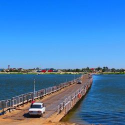 Boats in sea against clear blue sky