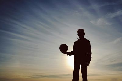 Low angle view of silhouette people standing against sky at sunset