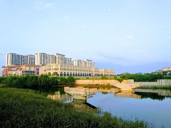 Buildings by lake against sky