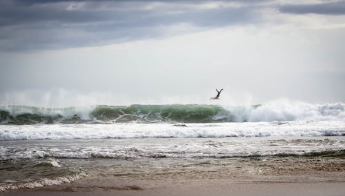 Full length of man in mid-air over waves in sea