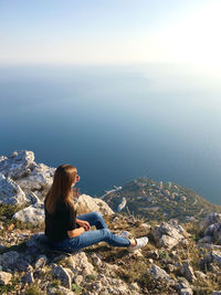 Woman sitting on rock looking at mountains