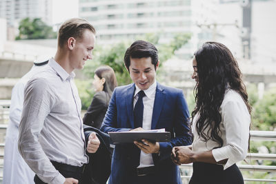 Business people discussing over file while standing outdoors