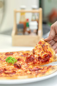 Close-up of hand holding pizza