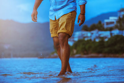 Low section of man standing in sea