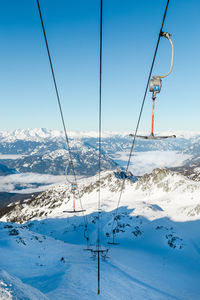 Ski lift over snowcapped mountains against sky