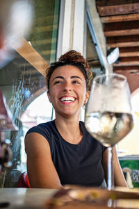 Smiling young woman with a glass of white wine on the table