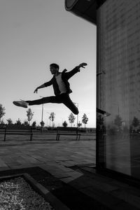 Young attractive dancer in casual cloth doing ballet jump on the urban