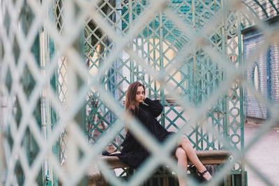 Portrait of woman seen through metal gate