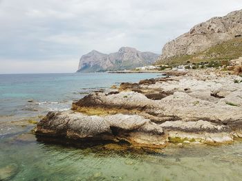 Rocks on shore by sea against sky