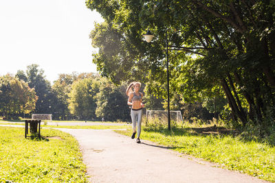 Woman standing by plants against trees