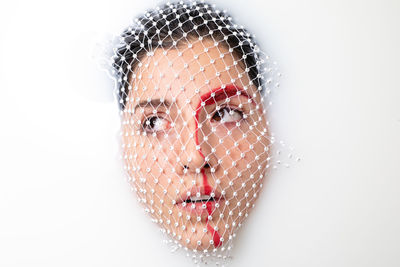 Close-up of thoughtful young woman with face covered by net taking milk bath