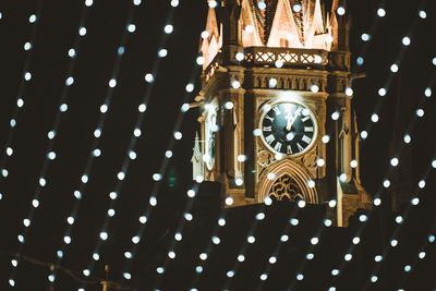 Low angle view of illuminated clock on ceiling in building