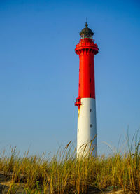 Lighthouse on field against sky