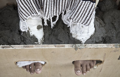 Low section of woman in wooden holes on mud