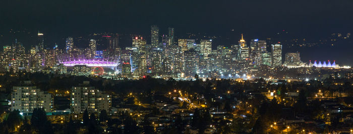 Illuminated cityscape against sky at night