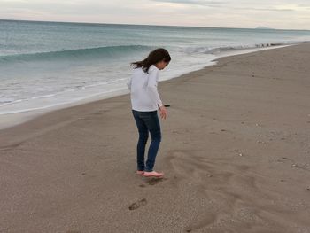 Full length of girl standing on beach against sea