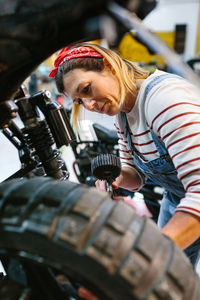Mechanic woman checking tire air pressure of motorcycle