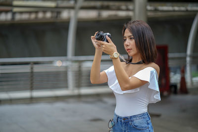 Woman photographing while standing outdoors