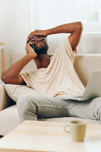 Young woman using laptop while sitting on bed at home