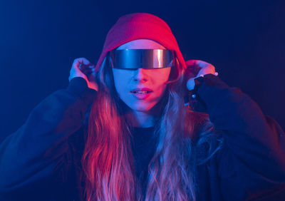 Portrait of young woman against black background