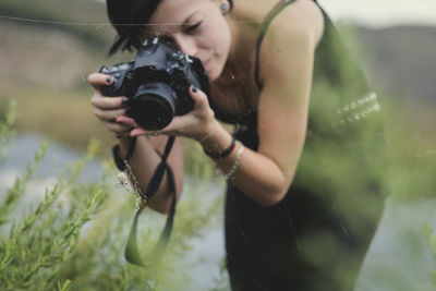 Woman photographing spider on web with camera