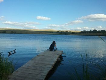 Rear view of woman sitting on pier