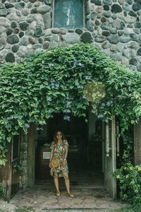 Portrait of woman standing by building entrance