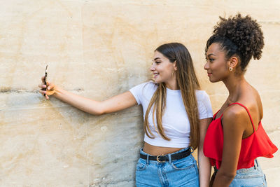 Happy woman standing against wall